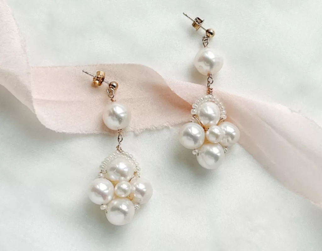Large real pearls statement earrings in gold with an ivory fabric background with blush silk ribbon. modern bridal earrings for your wedding day