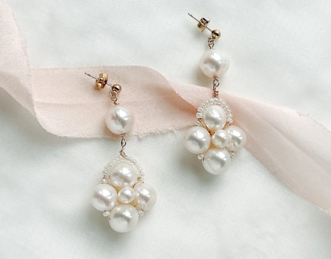 Large real pearls statement earrings in gold with an ivory fabric background with blush silk ribbon. modern bridal earrings for your wedding day